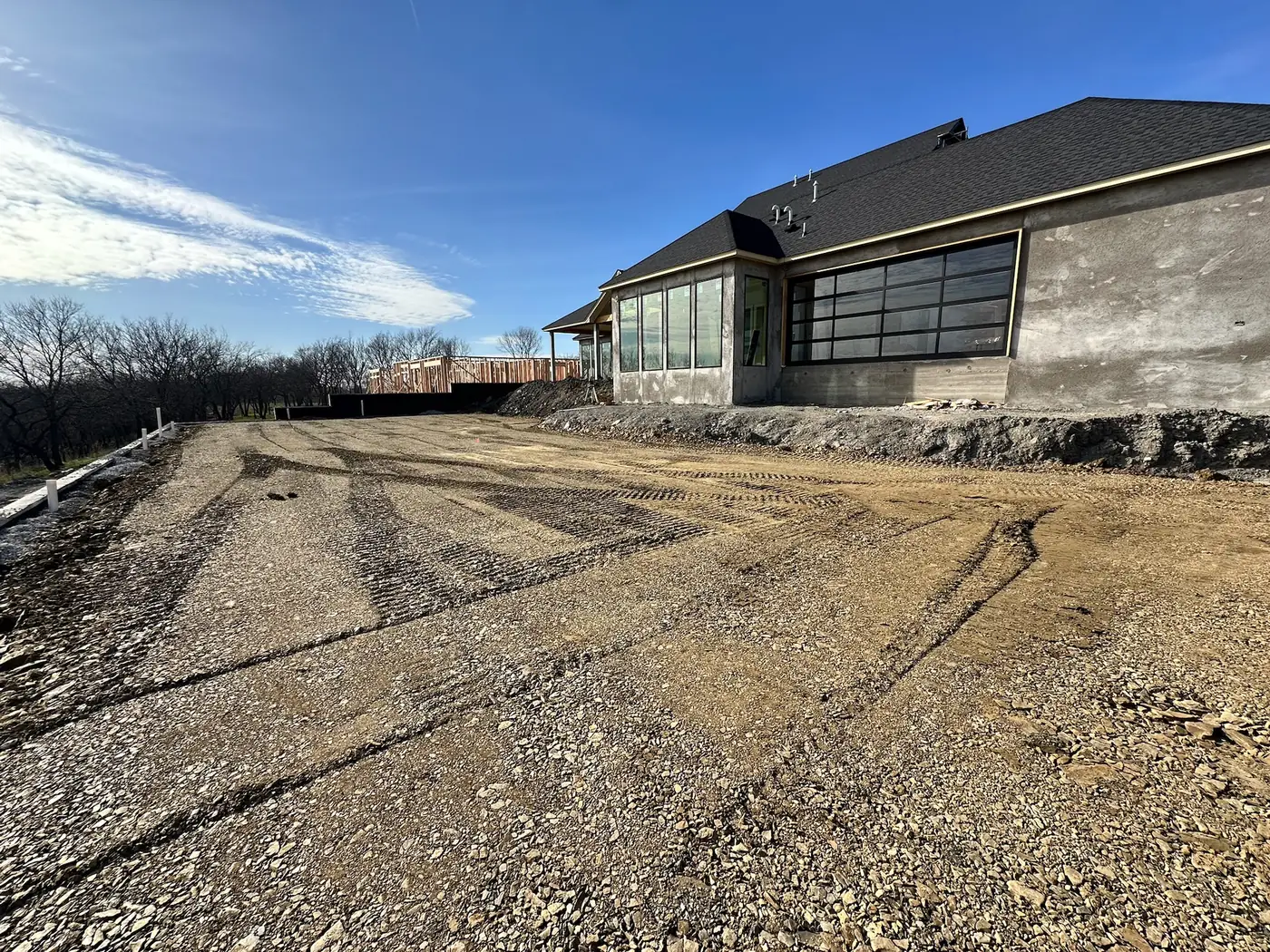 Finished residential grading and gravel preparation beside a modern home
