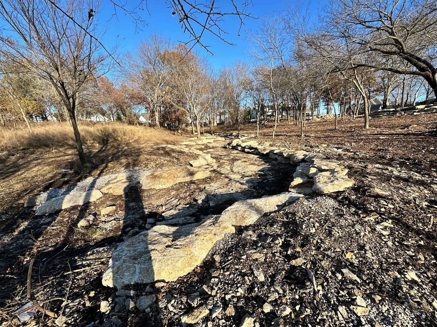Rock-lined drainage swale running through a wooded property