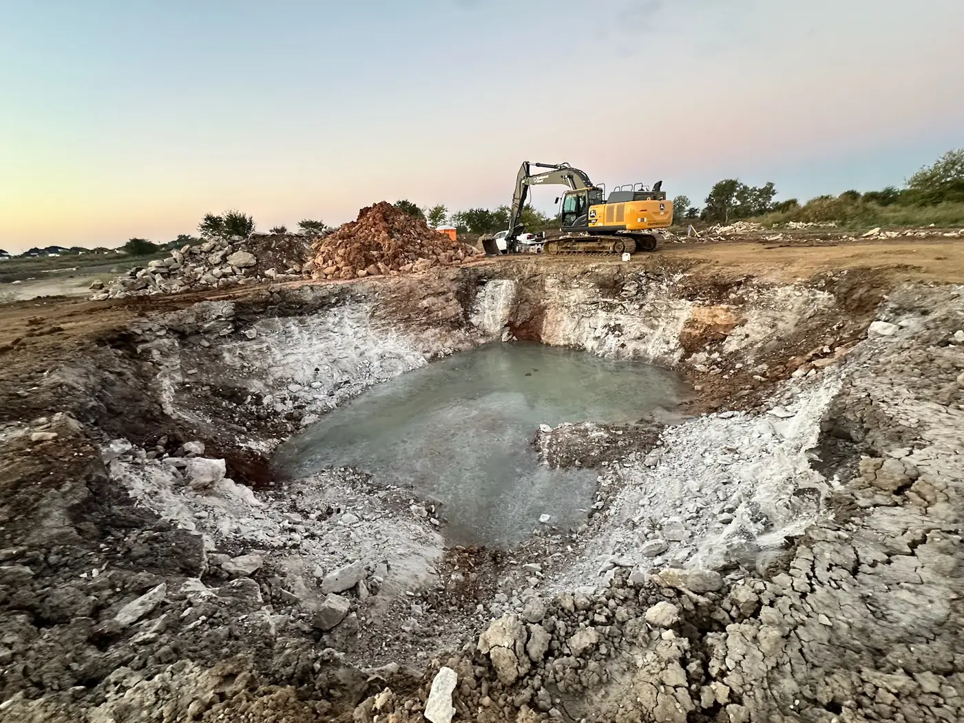 Large excavator working in a rock excavation at dusk