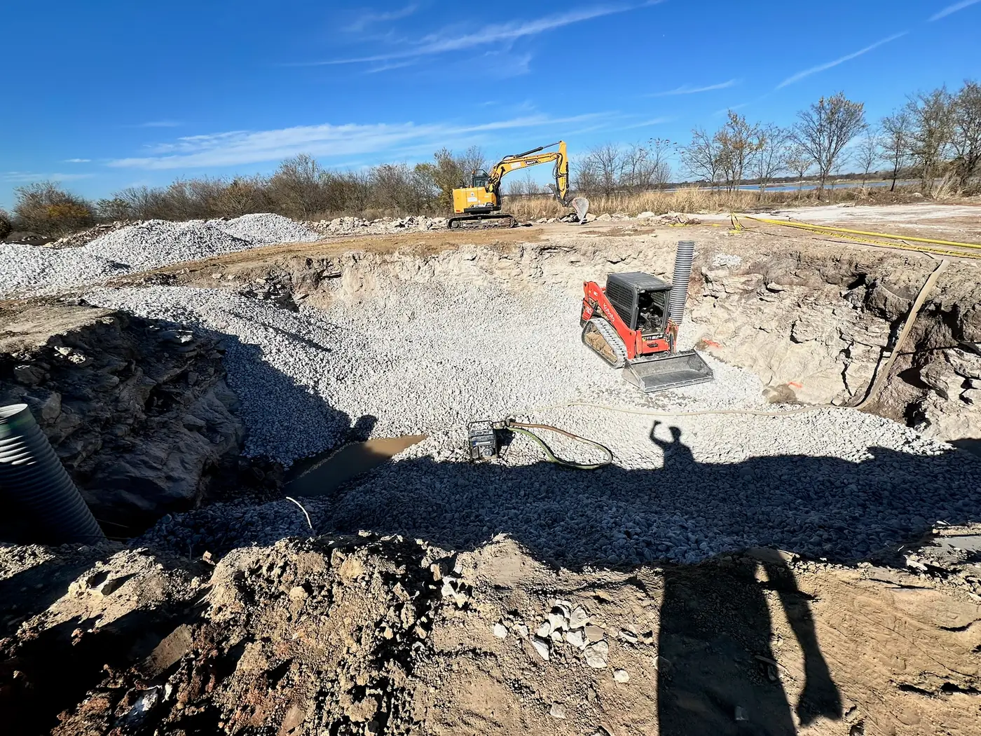 Excavator and skid steer preparing a deep construction area
