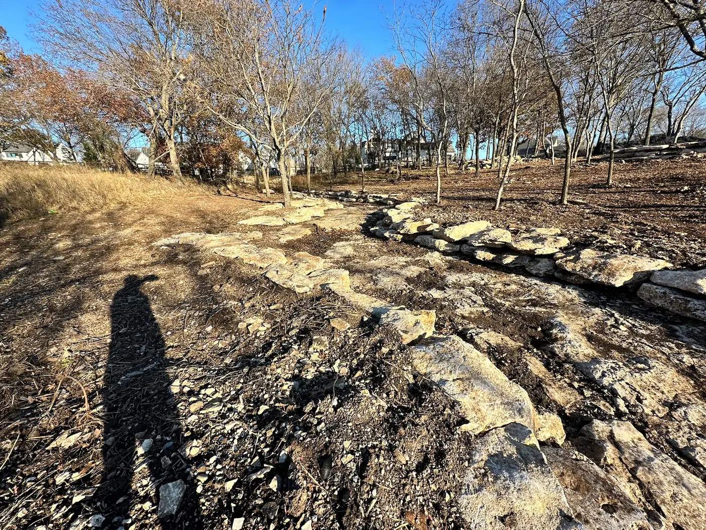 Stone drainage channel integrated into a landscaped slope