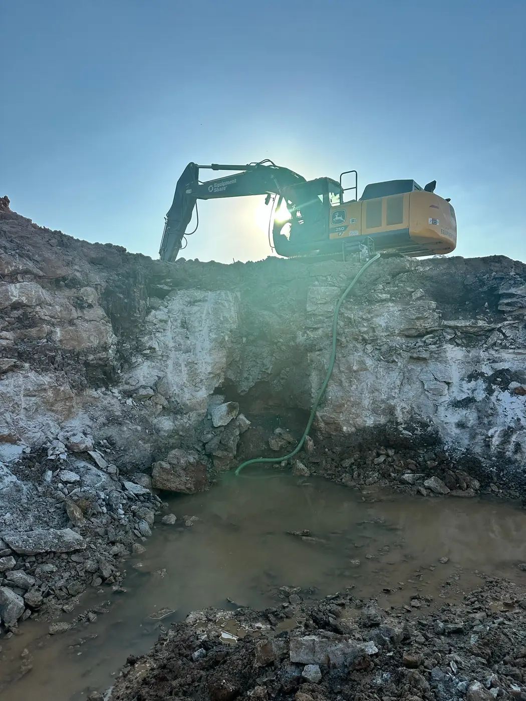 Excavator digging through rock and water on a deep project