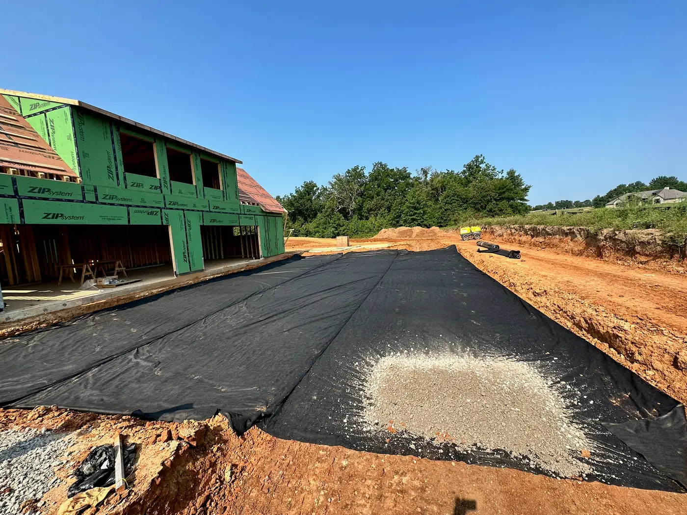 Geotextile and gravel base installed beside a new home