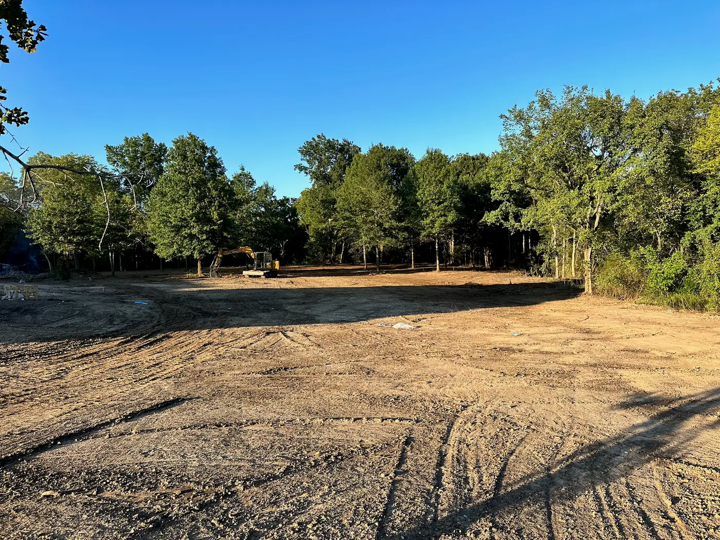 Excavator clearing a wooded residential lot in the Tulsa area