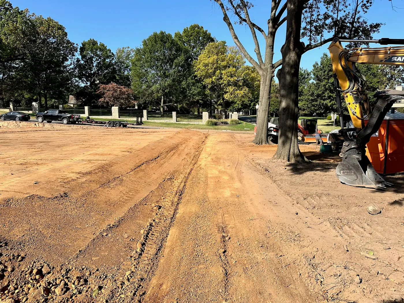 Excavator grading a homesite near a mature tree